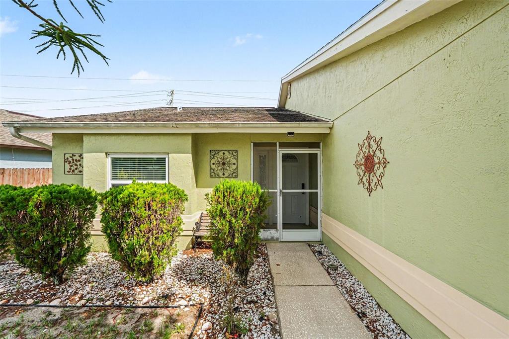 The exterior of a light green house features a walkway leading to a screened front door — 8434 SUN DRIVE, PORT RICHEY, FL