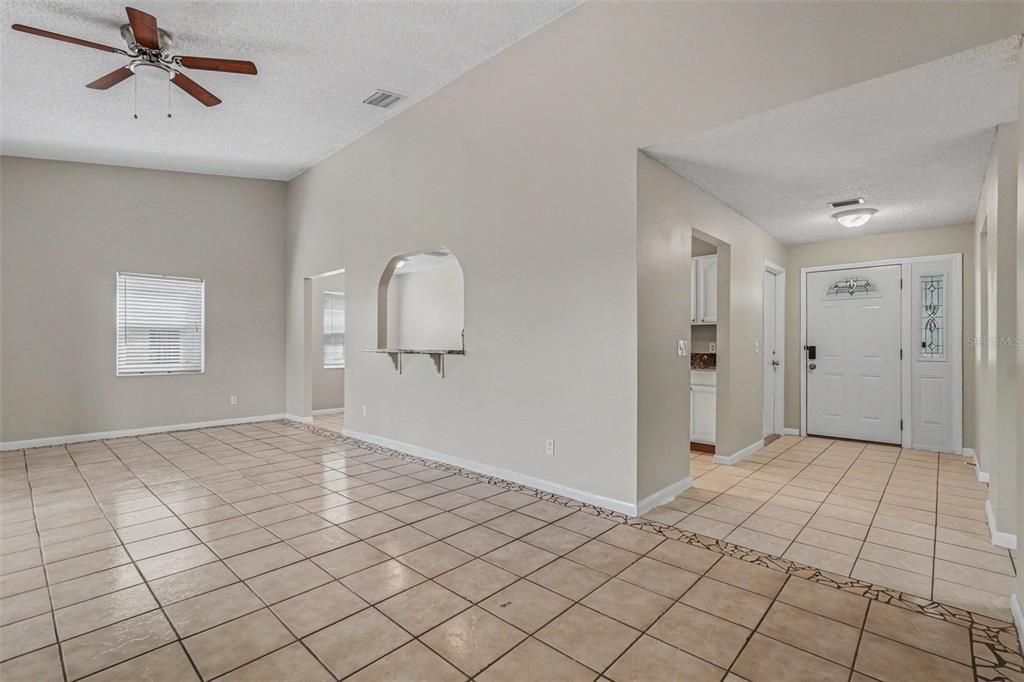 A living room with beige tile floors, a ceiling fan, and an arched wall cutout — 8434 SUN DRIVE, PORT RICHEY, FL