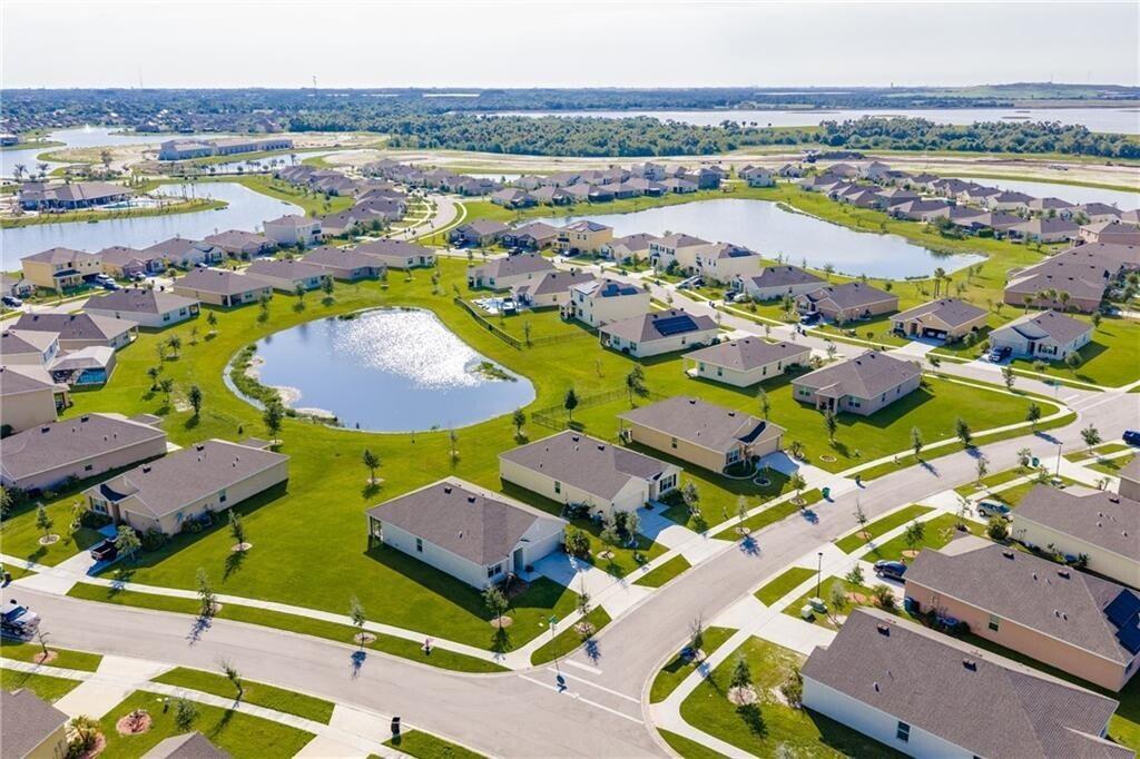 An aerial view shows a suburban neighborhood with houses surrounding several small ponds — 3453 Trinity Circle, Fort Pierce FL 34945, FORT PIERCE, FL