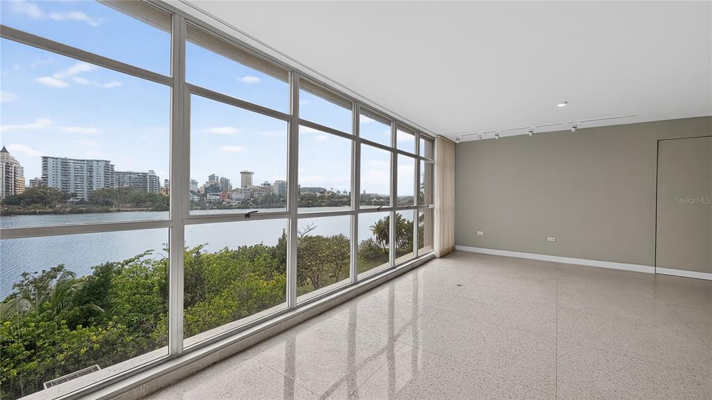 An empty room with light-colored tile flooring and a wall of windows overlooking water — 860 ASHFORD AVENUE #5C UNIT 1, SAN JUAN, PR