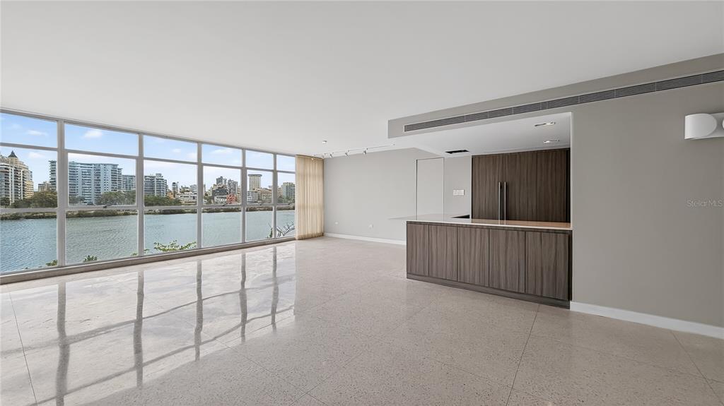 An open-plan living area features large windows, light tile flooring, and a dark wood bar — 860 ASHFORD AVENUE #5C UNIT 1, SAN JUAN, PR