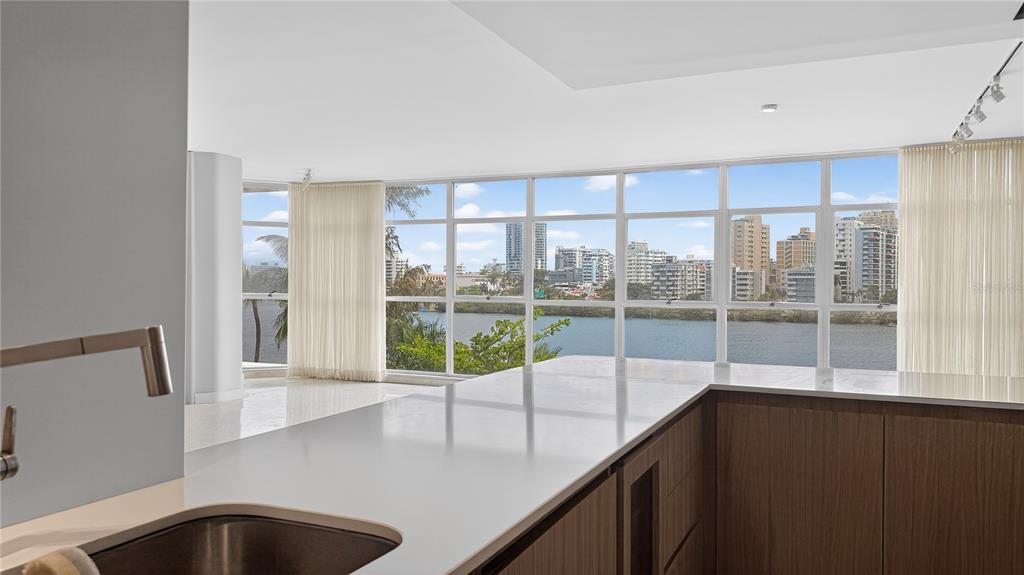A modern kitchen with white countertops overlooks a waterfront view of a city skyline — 860 ASHFORD AVENUE #5C UNIT 1, SAN JUAN, PR