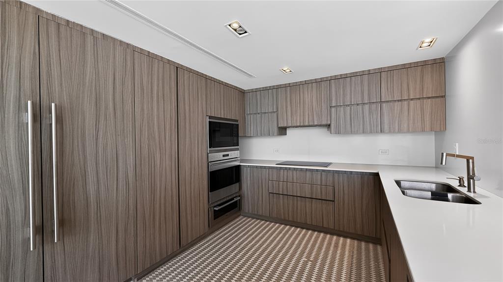 A modern kitchen features wood-grain cabinetry, white countertops, a double wall oven, and patterned flooring — 860 ASHFORD AVENUE #5C UNIT 1, SAN JUAN, PR