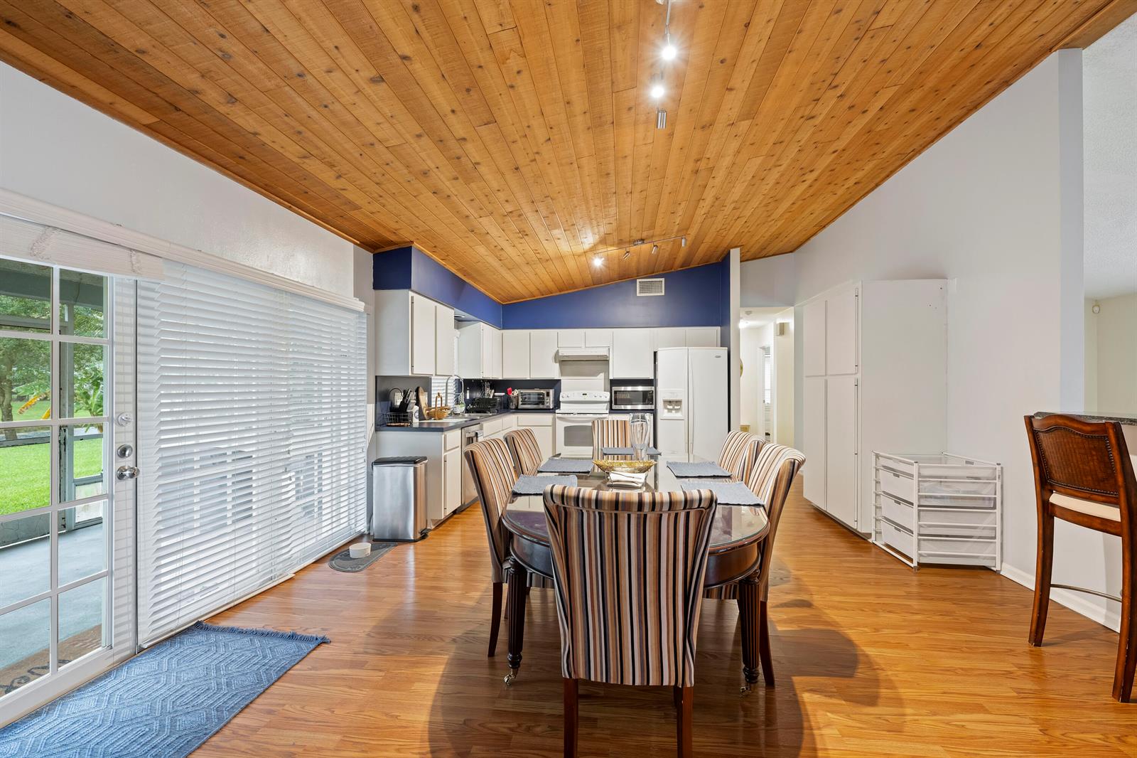 A dining area with a wood-paneled vaulted ceiling, striped chairs, and an adjacent kitchen — 756 Juniper Place, Wellington FL 33414, WELLINGTON, FL