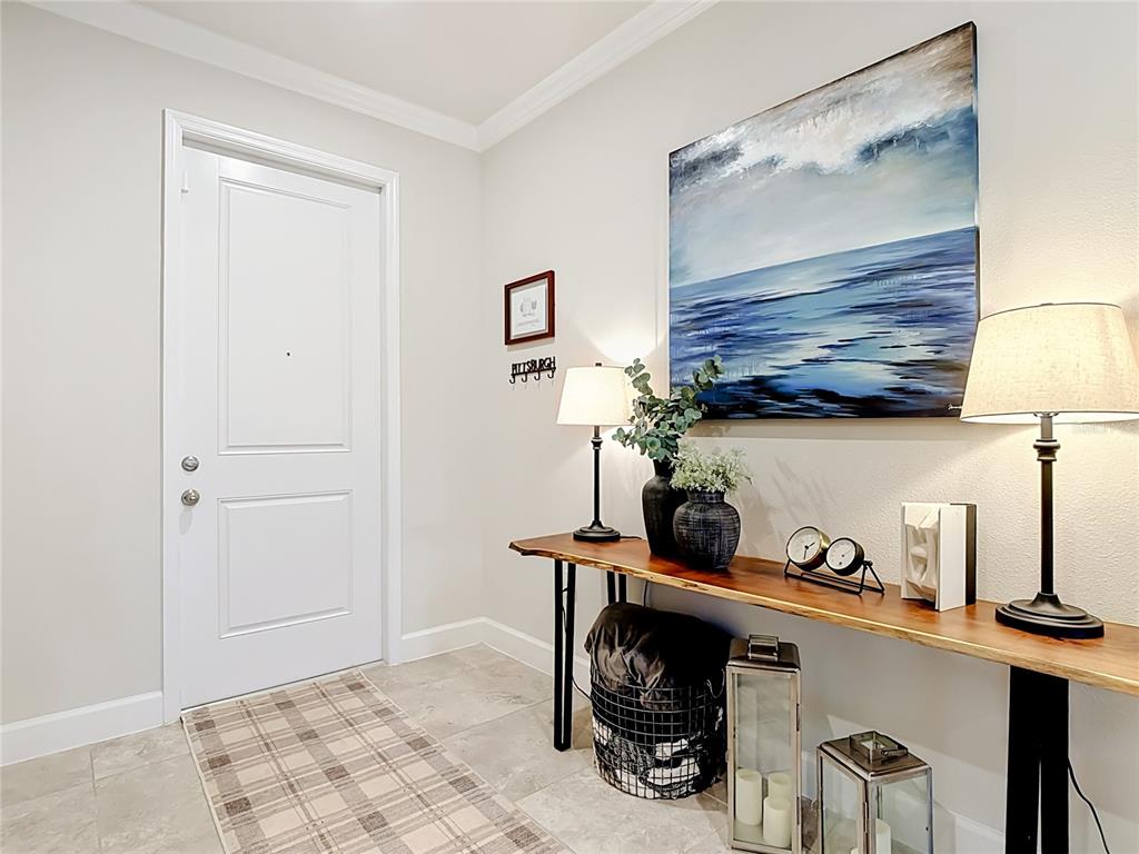 A foyer features a live-edge console table, a large seascape painting, and a plaid rug — 5757 ANDERS WAY, ST CLOUD, FL