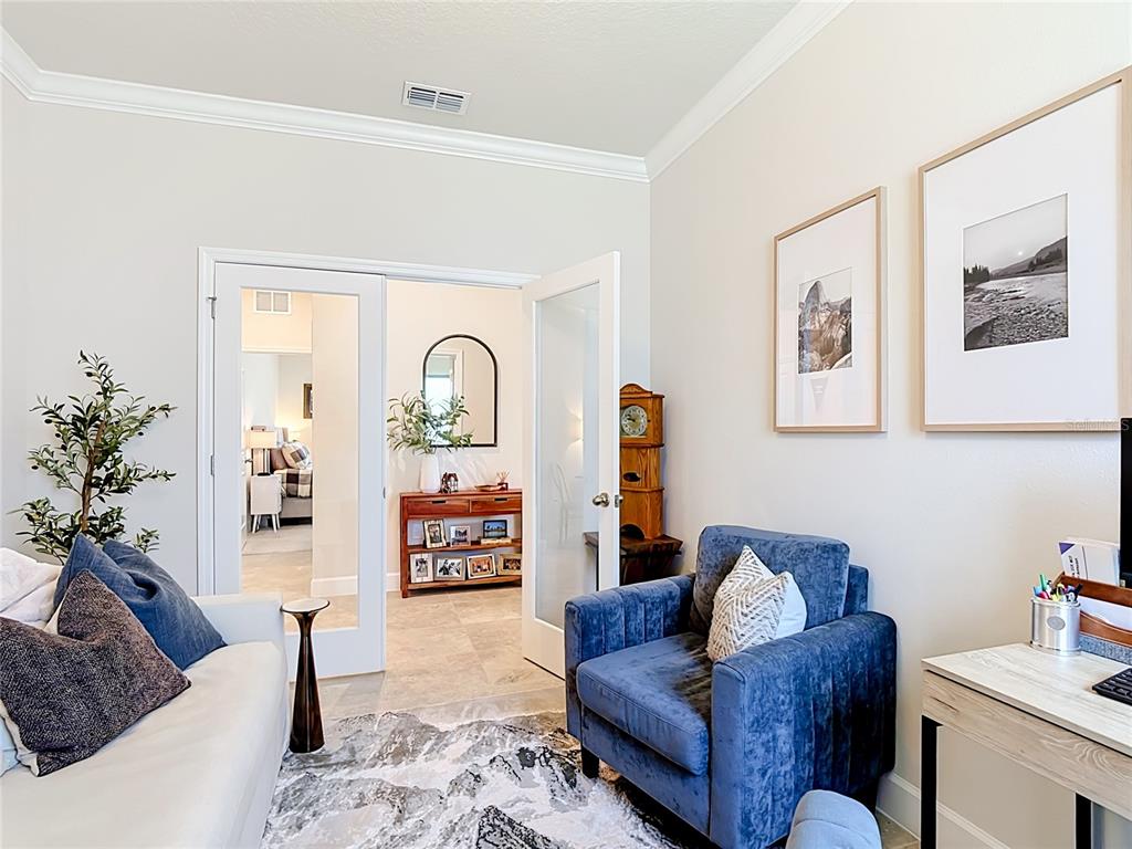 A room with a blue armchair, a white sofa, and glass doors leading to another room — 5757 ANDERS WAY, ST CLOUD, FL
