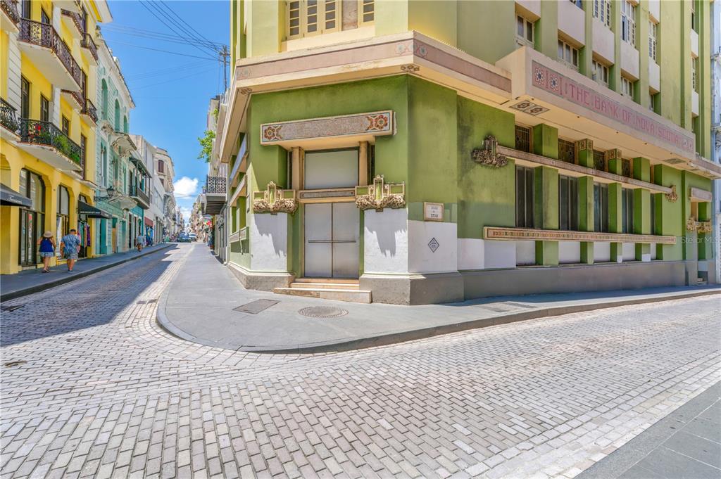 A corner view of a green historic building with decorative details on a cobblestone street — 251/253 TETUAN STREET, SAN JUAN, PR