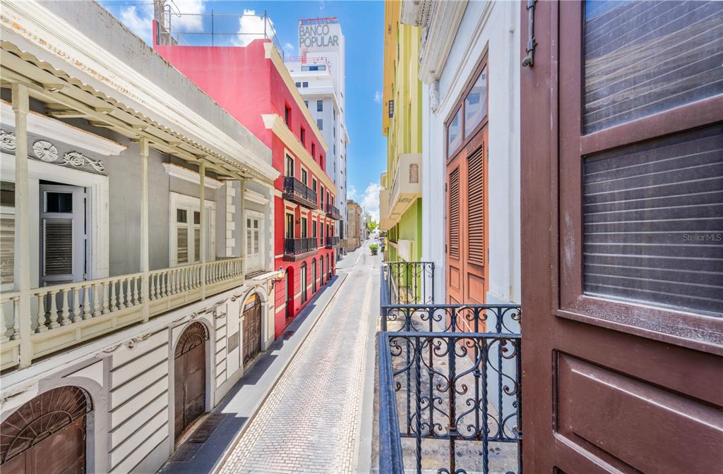 A view from a balcony overlooking a narrow cobblestone street lined with colorful historic buildings — 251/253 TETUAN STREET, SAN JUAN, PR