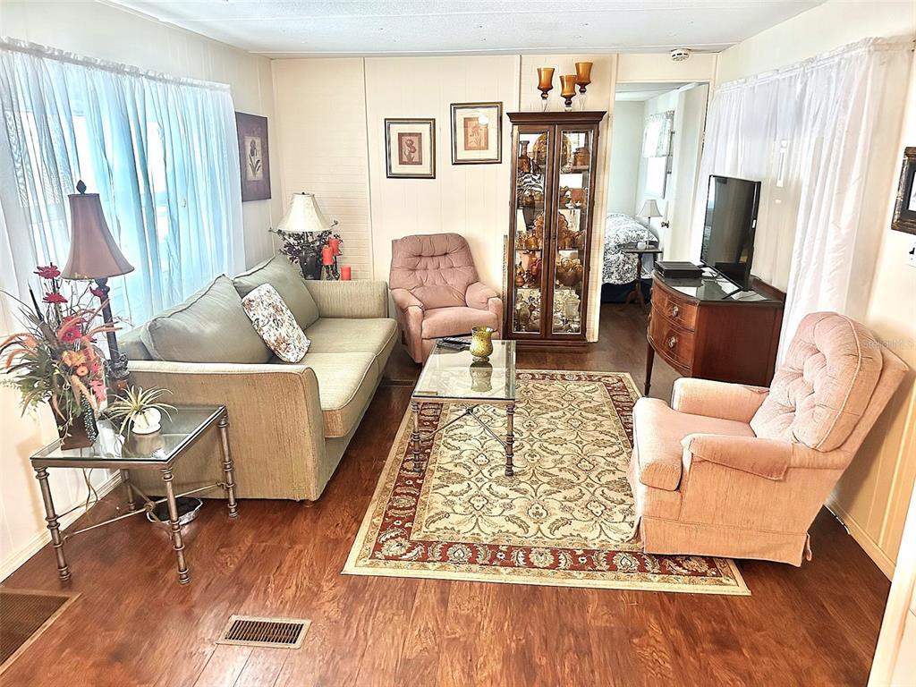 A living room features a sofa, two armchairs, a glass coffee table, and wood flooring — 9790 66TH STREET N UNIT 265, PINELLAS PARK, FL