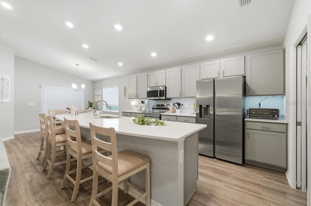 A modern kitchen features light gray cabinets, stainless steel appliances, and a large white island — 2610 SAN MARCO WAY, WINTER HAVEN, FL