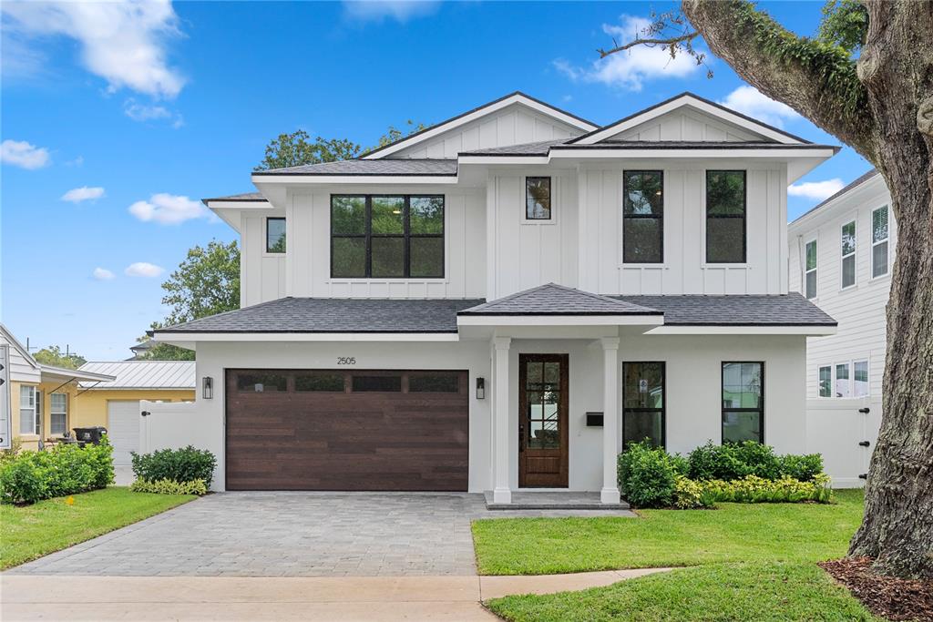 A two-story modern house with white vertical siding, a wood garage door, and a front porch — 2505 AMHERST AVENUE, ORLANDO, FL
