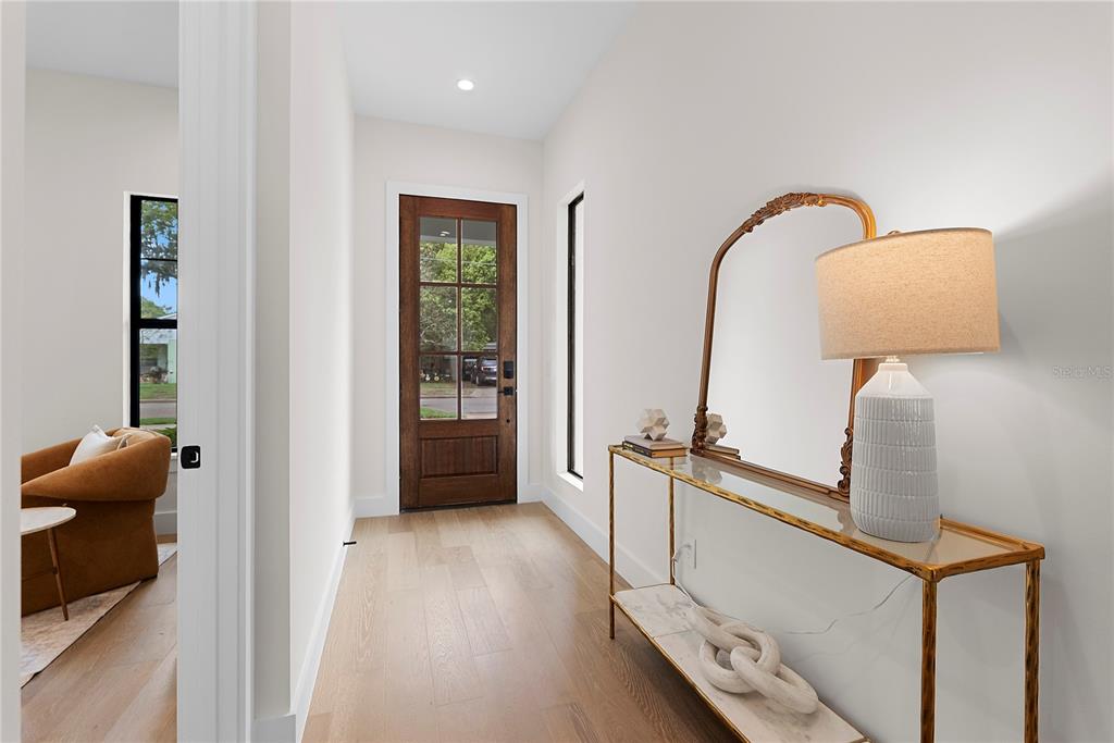 A bright entryway features a wood front door, light hardwood floors, and a console table — 2505 AMHERST AVENUE, ORLANDO, FL