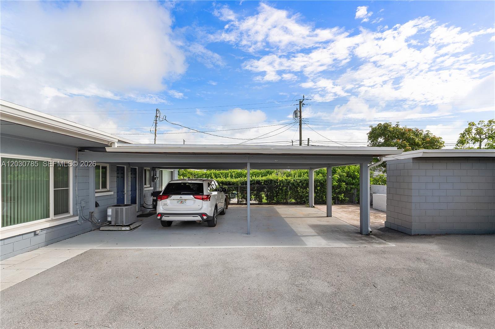 A white SUV is parked under a covered carport attached to a gray house — 204 NW 1st St, Boynton Beach FL 33435, BOYNTON BEACH, FL