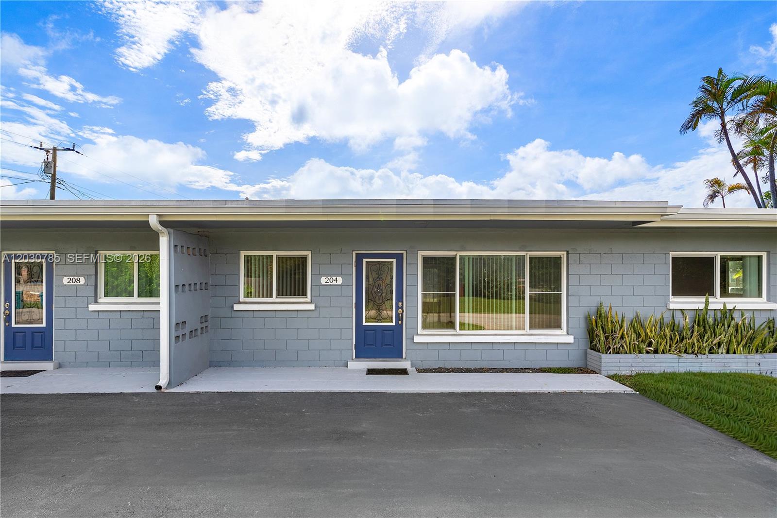 The exterior of a gray concrete block building features two blue doors and large windows — 204 NW 1st St, Boynton Beach FL 33435, BOYNTON BEACH, FL