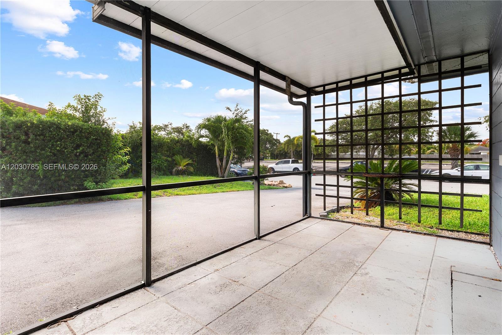 A screened-in patio features a concrete floor, a metal roof, and a decorative lattice wall — 204 NW 1st St, Boynton Beach FL 33435, BOYNTON BEACH, FL
