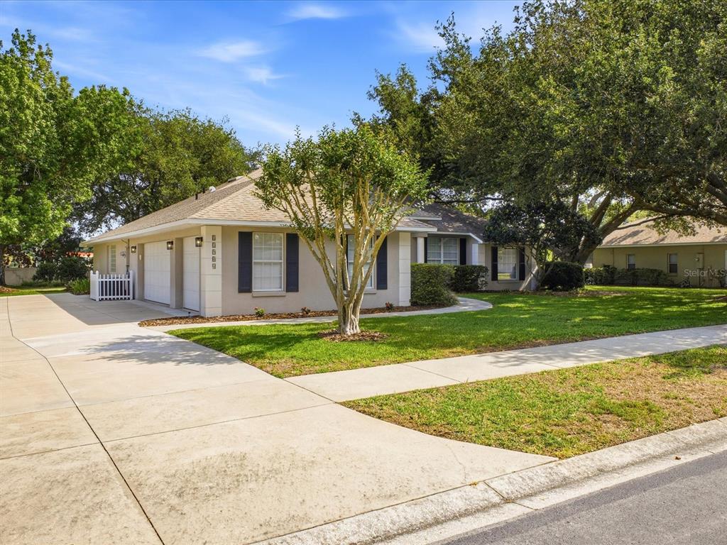 A single-story house with a beige exterior, dark shutters, and a concrete driveway — 11906 GRACES WAY, CLERMONT, FL