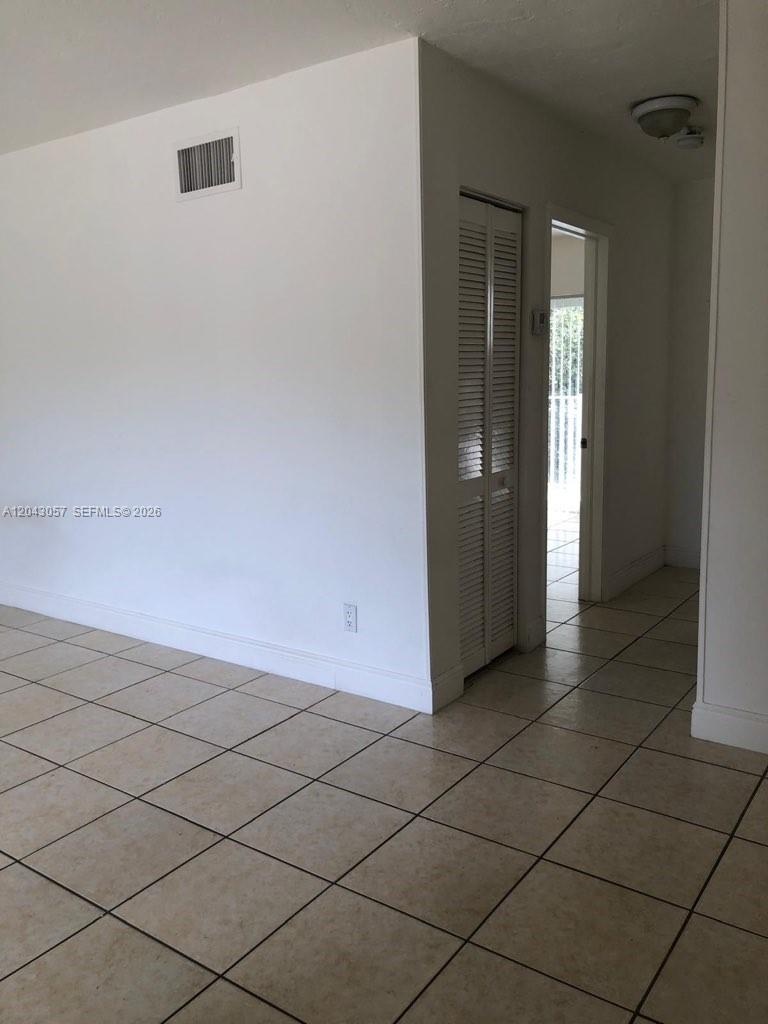 A room with light-colored tile flooring, white walls, and a louvered closet door — 1895 Venice Park Dr # B20, Miami FL 33181, MIAMI, FL