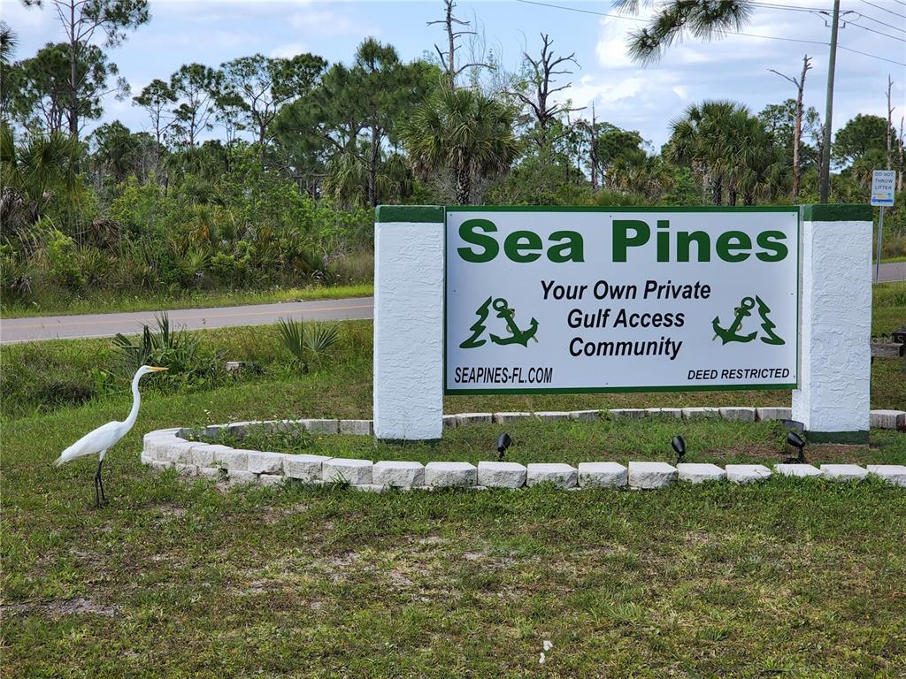 A white egret stands on the grass in front of a Sea Pines community sign — Lot 143 & 145 INWOOD DRIVE, HUDSON, FL