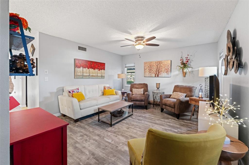 A living room features a white sofa, two brown armchairs, and wood-look flooring — 300 S FLORIDA AVENUE UNIT 600F, TARPON SPRINGS, FL