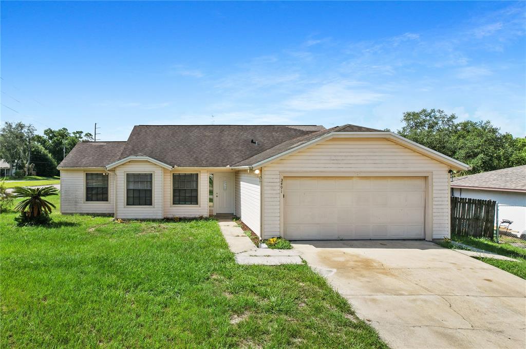 A single-story house with light-colored siding, a two-car garage, and a front lawn — 3491 MONUMENT DRIVE, DELTONA, FL