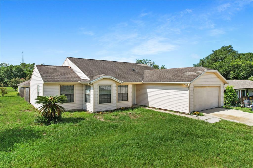 A single-story house with beige siding, a two-car garage, and a grassy front yard — 3491 MONUMENT DRIVE, DELTONA, FL