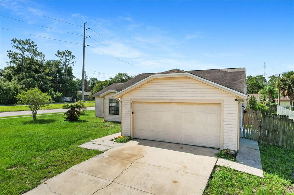 A single-story house with a beige exterior, a two-car garage, and a concrete driveway — 3491 MONUMENT DRIVE, DELTONA, FL