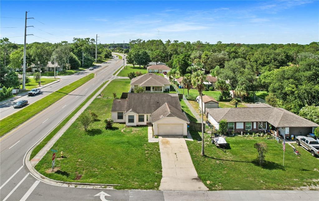An aerial view shows a suburban house with a driveway and lawn near a road — 3491 MONUMENT DRIVE, DELTONA, FL