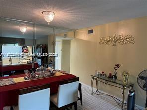 A dining area features a red-clothed table, mirrored walls, and a glass console table — 3571 Inverrary Dr # 408, Lauderhill FL 33319, LAUDERHILL, FL