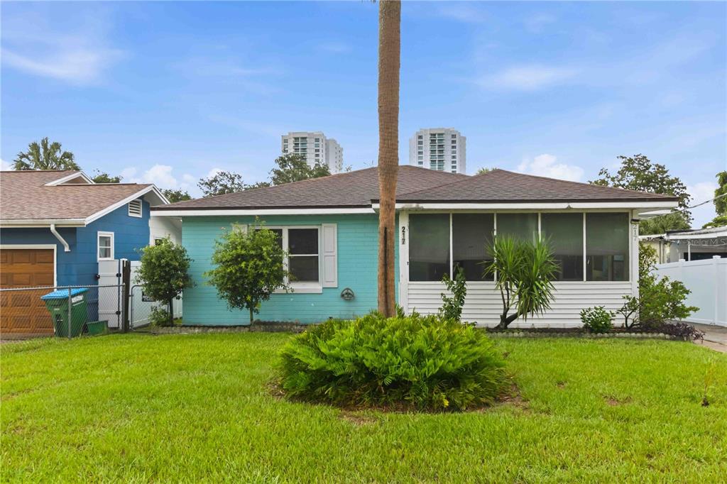 A single-story house with turquoise siding and a screened-in porch sits behind a palm tree — 217 DAYTONA AVENUE, HOLLY HILL, FL