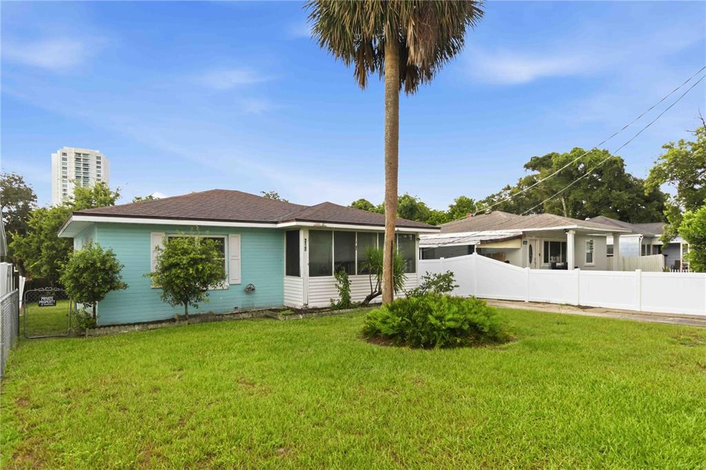 A light blue single-story house with a screened-in porch and a tall palm tree — 217 DAYTONA AVENUE, HOLLY HILL, FL