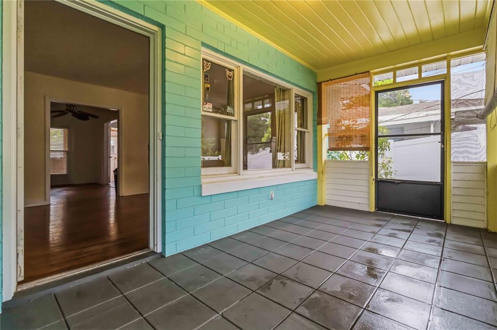 A covered porch with teal painted brick walls, a yellow ceiling, and dark tiled flooring — 217 DAYTONA AVENUE, HOLLY HILL, FL