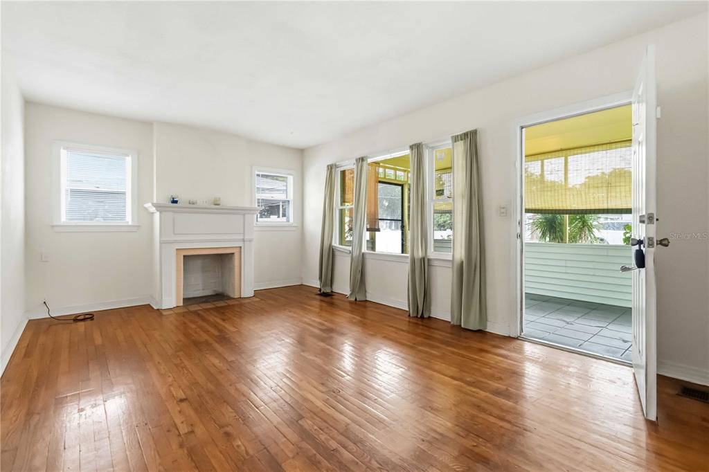 A living room with hardwood floors, a fireplace, and a door leading to a porch — 217 DAYTONA AVENUE, HOLLY HILL, FL