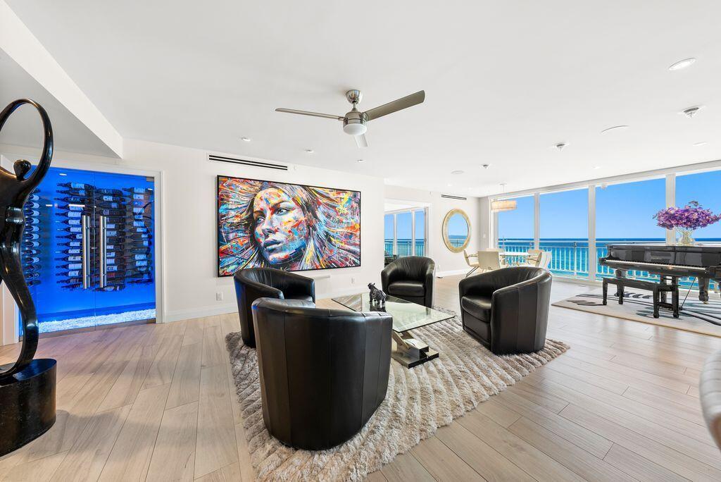 A modern living room features a glass wine cellar, colorful wall art, and ocean views — 2150 N Ocean Boulevard # s, Boca Raton FL 33431, BOCA RATON, FL