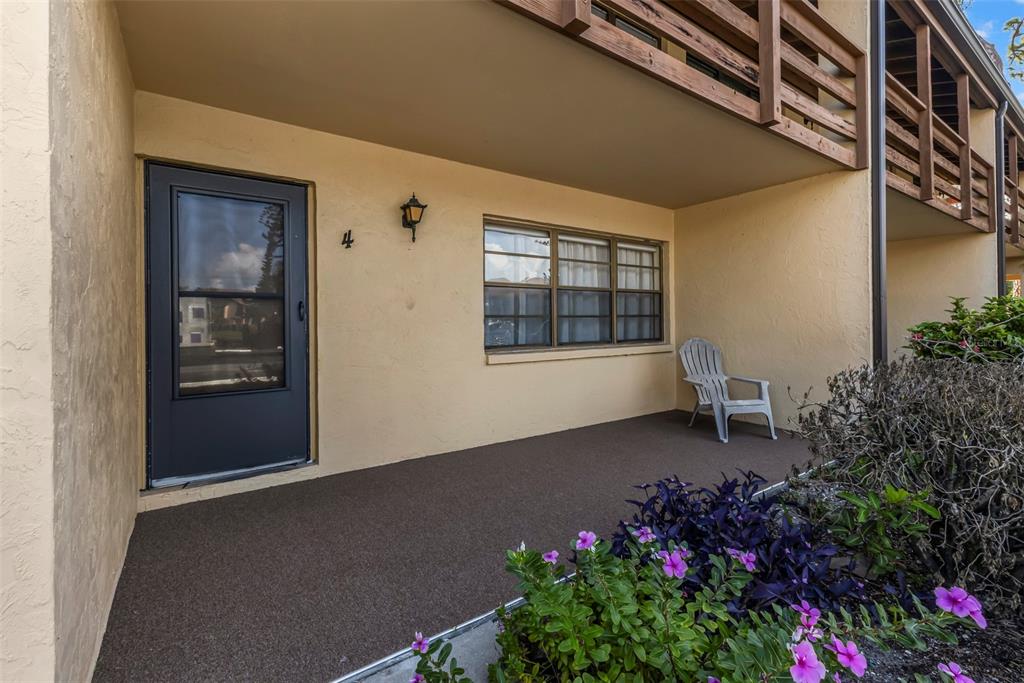 A covered patio features a dark door marked with the number four and a window — 8 QUAILS RUN BOULEVARD UNIT 4, ENGLEWOOD, FL