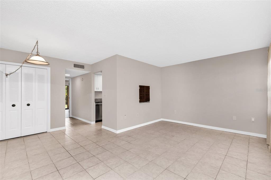 An empty room with beige walls, tile flooring, a closet, and an open kitchen doorway — 8 QUAILS RUN BOULEVARD UNIT 4, ENGLEWOOD, FL