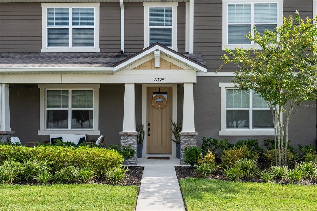 The exterior of a two-story house features a covered porch, stone columns, and a front door — 11574 BUOY POINT PLACE, ORLANDO, FL