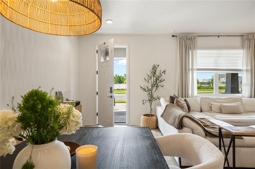 A dining area with a dark table opens into a living room with a white sofa — 11574 BUOY POINT PLACE, ORLANDO, FL