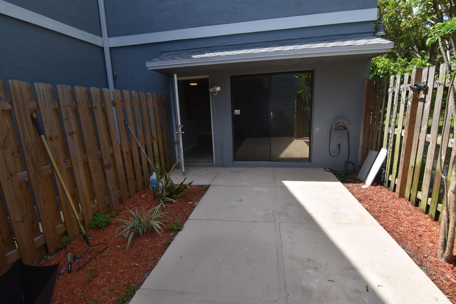A concrete patio sits outside a sliding glass door and an open door of a home — 3 Crossings Circle # B, Boynton Beach FL 33435, BOYNTON BEACH, FL