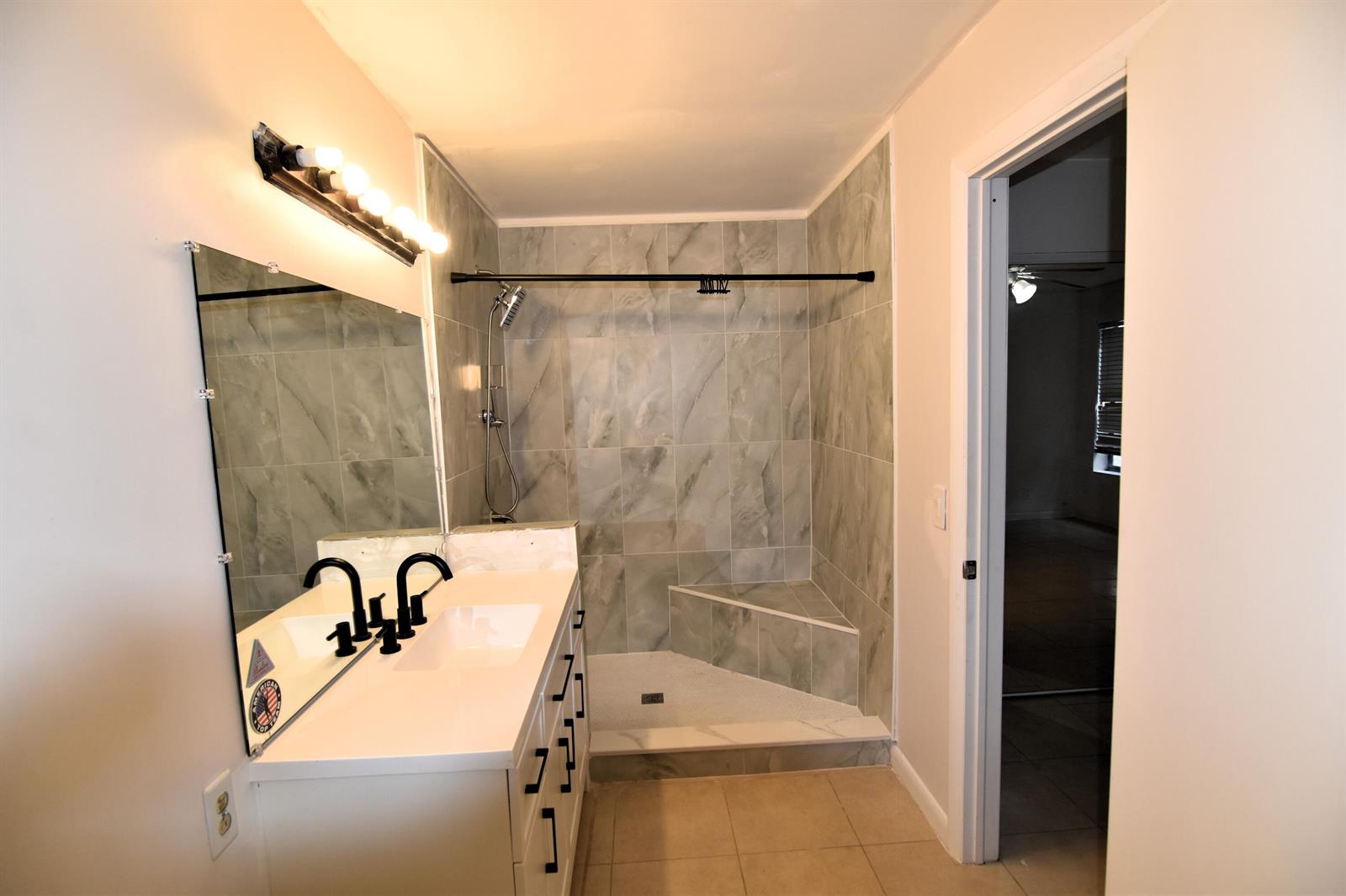A bathroom features a white vanity with a black faucet, a mirror, and a tiled shower — 3 Crossings Circle # B, Boynton Beach FL 33435, BOYNTON BEACH, FL