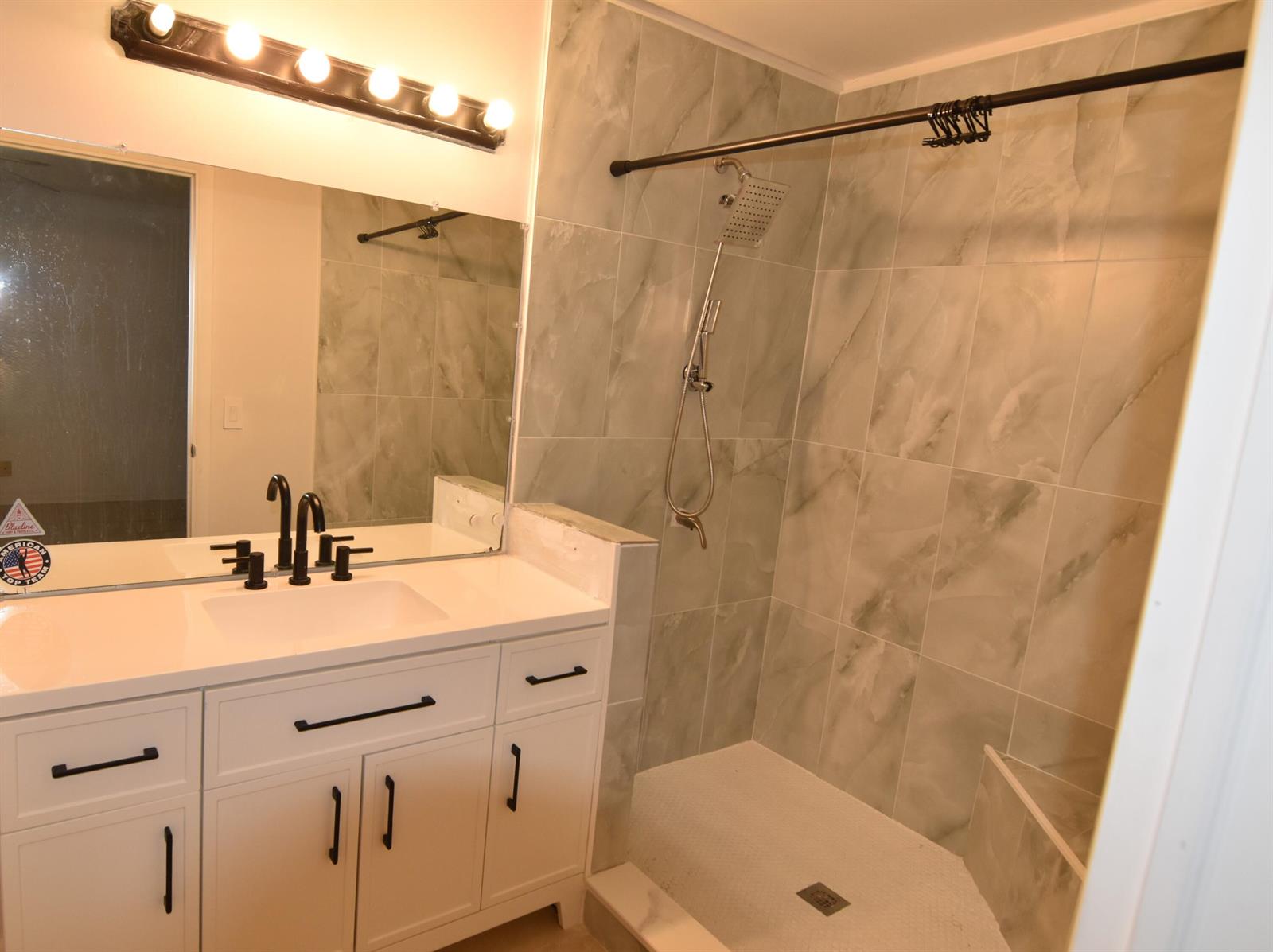A bathroom features a white vanity with black hardware, a mirror, and a tiled shower — 3 Crossings Circle # B, Boynton Beach FL 33435, BOYNTON BEACH, FL