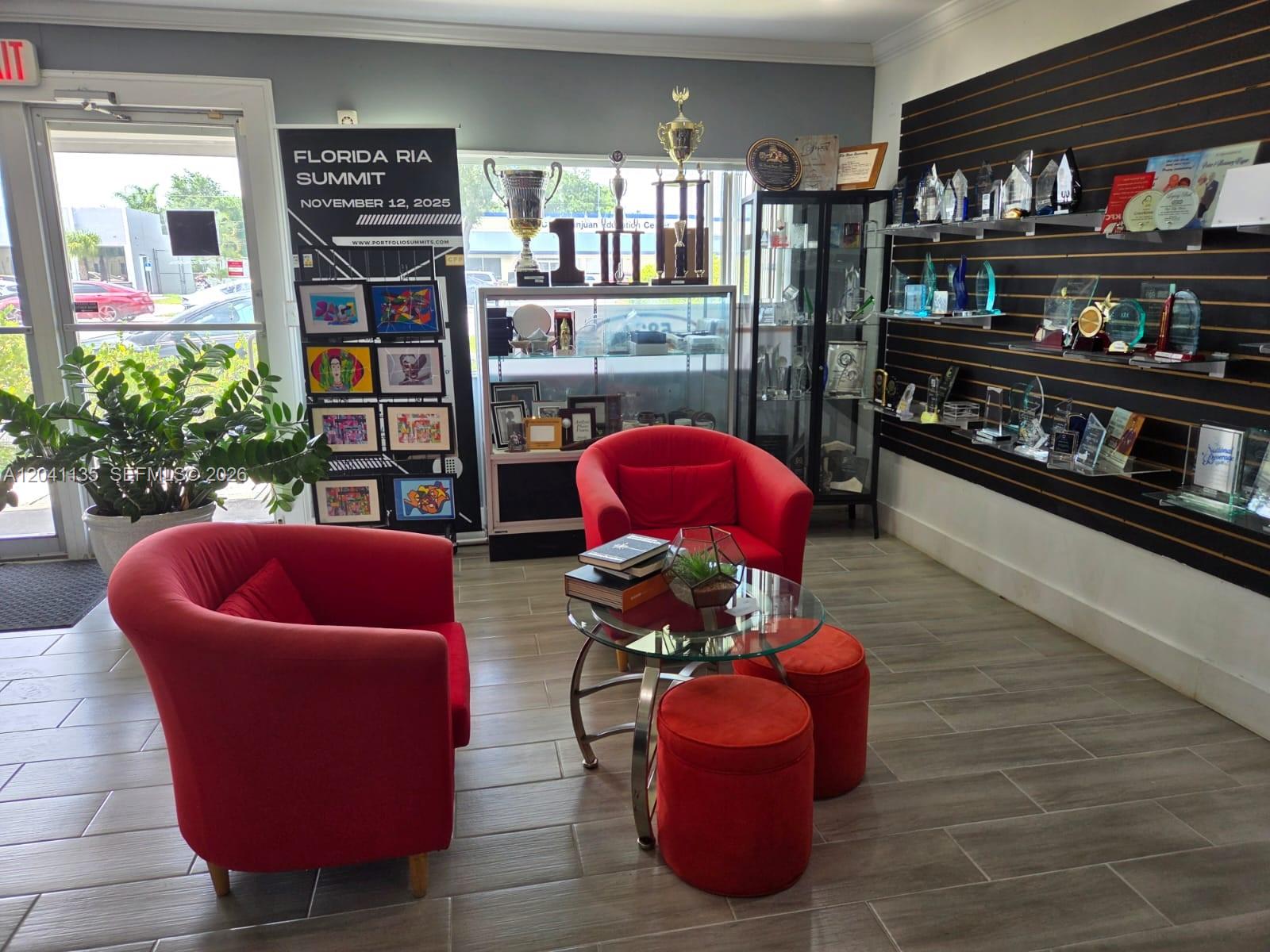 A waiting area features two red armchairs, a glass coffee table, and shelves displaying trophies — 5824 Johnson St, Hollywood FL 33021, HOLLYWOOD, FL