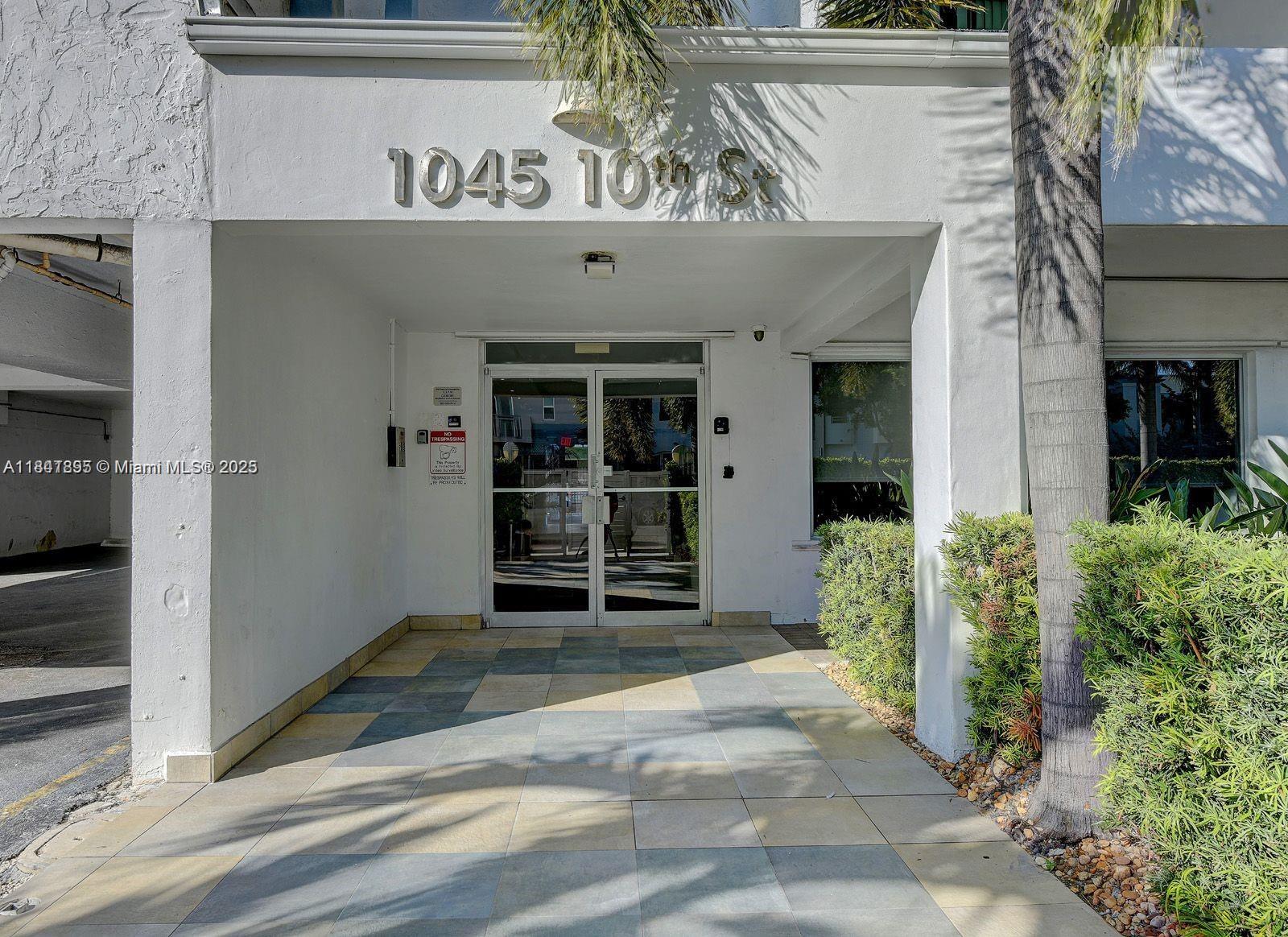 The exterior entrance of a building features a glass double door under a covered walkway — 1045 10th St # 907, Miami Beach FL 33139, MIAMI BEACH, FL