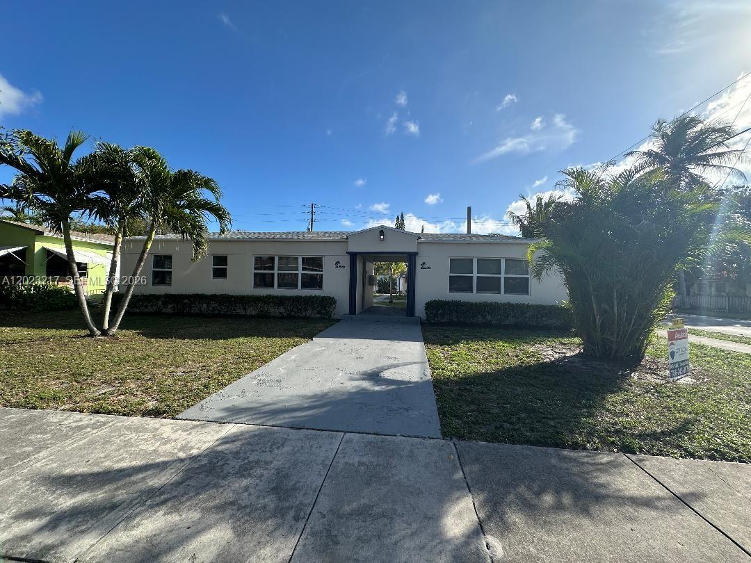 A single-story residential building features a central breezeway, a concrete walkway, and surrounding palm trees — 1956 Lincoln St # 5, Hollywood FL 33020, HOLLYWOOD, FL