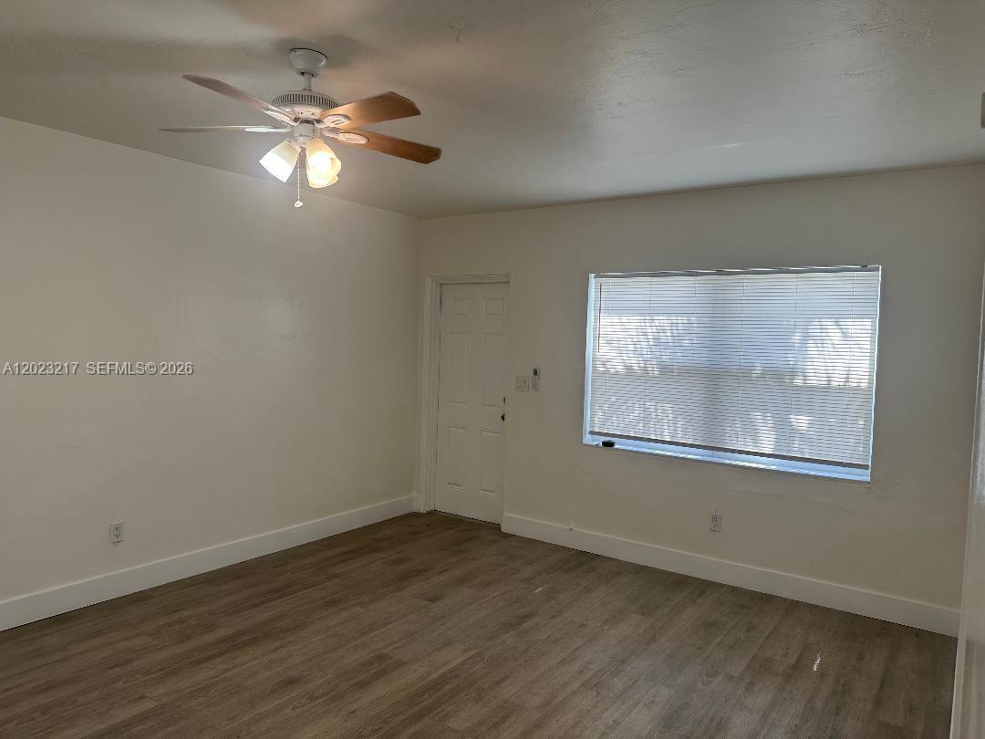 An empty room features light-colored walls, wood-look flooring, a ceiling fan, and a window — 1956 Lincoln St # 5, Hollywood FL 33020, HOLLYWOOD, FL