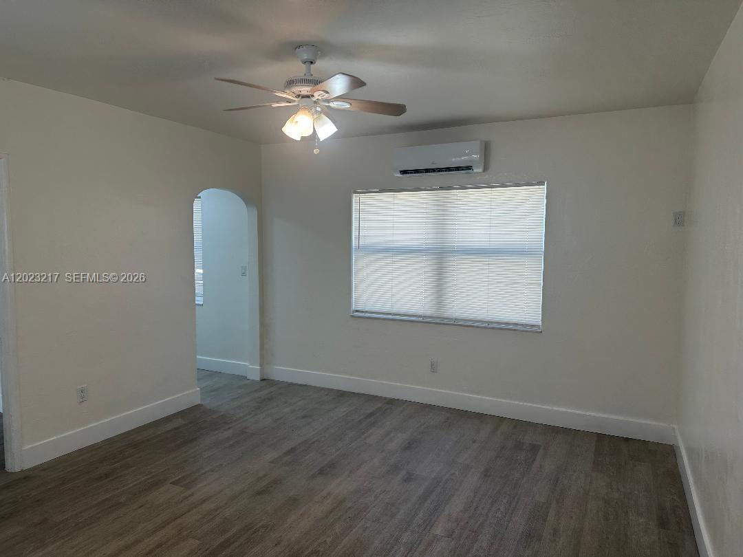 An empty room features light-colored walls, wood-look flooring, a ceiling fan, and a wall-mounted air conditioner — 1956 Lincoln St # 5, Hollywood FL 33020, HOLLYWOOD, FL