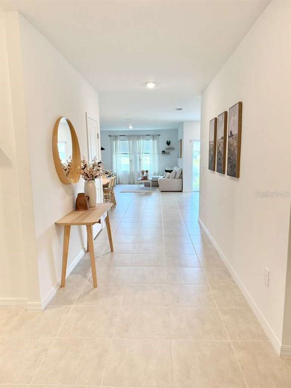 A tiled hallway leads to a living area with a console table and wall art — 4773 YELLOW ELDER WAY, KISSIMMEE, FL