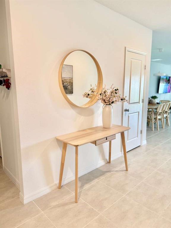 A light wood console table with a round mirror and vase sits in a hallway — 4773 YELLOW ELDER WAY, KISSIMMEE, FL