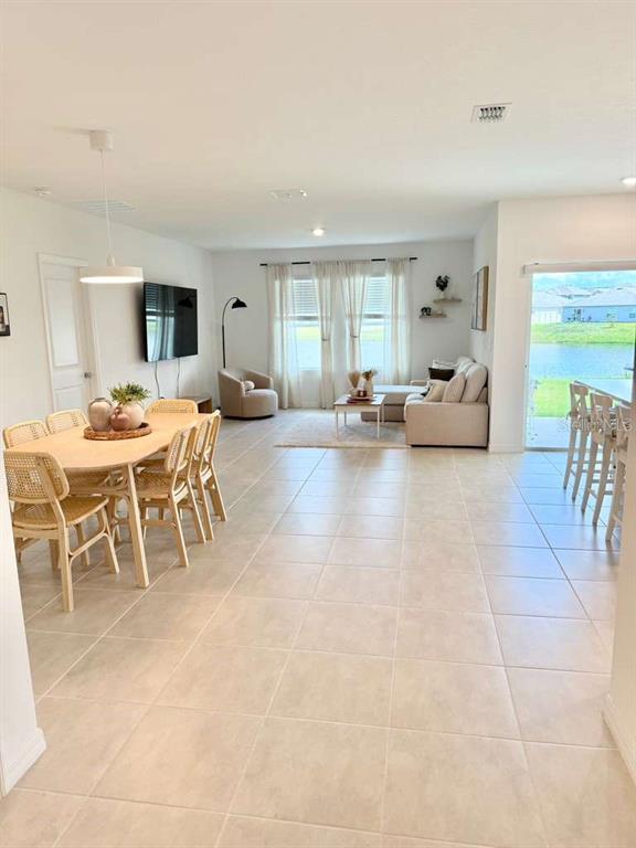 An open-concept living and dining area features tile flooring, neutral walls, and large windows — 4773 YELLOW ELDER WAY, KISSIMMEE, FL