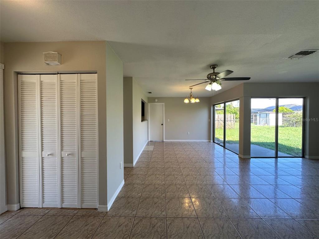 A room with tiled floors, a ceiling fan, and sliding glass doors leading to a yard — 707 WEDGE LANE, POINCIANA, FL