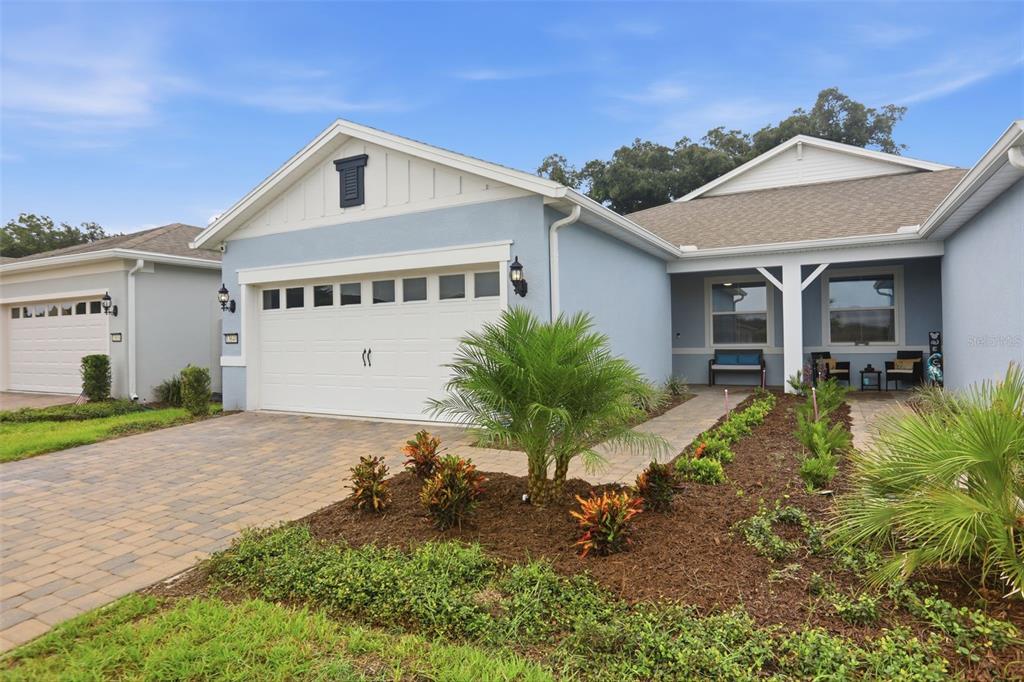 A light blue single-story house features a two-car garage and a paved driveway — 13640 SPLASHING ISLA DRIVE, WINTER GARDEN, FL